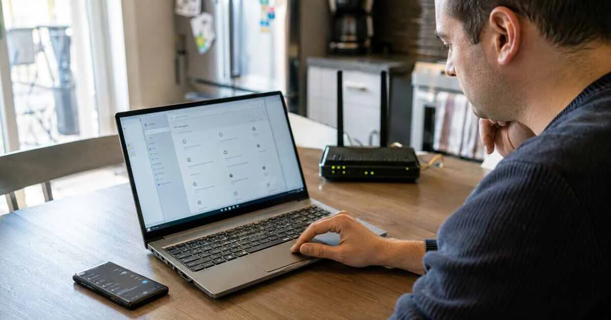 Windows laptop being checked beside a home router after losing internet access